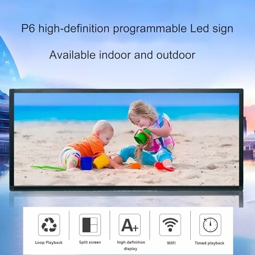 Two children playing with sand on a beach displayed on a high-definition LED sign.